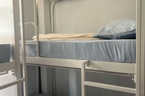 A bunk bed with a mattress and pillow, metal railings, and a small storage compartment. - JC Home Stay (Bangkok)
