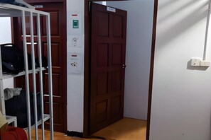 A hotel room with a wardrobe, a door with a sign, and a light switch on the wall. - JC Home Stay (Bangkok)