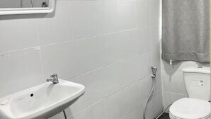 Une salle de bain avec un lavabo blanc, un miroir et des toilettes.