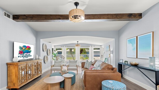 A spacious living room with a high ceiling, wooden beams, a large window, and a view of the outdoors. - MiniGolf/Game Room/Disc Golf/PacMan/Pool Table/Shuffleboard- 9 min to Beach (St. Petersburg)