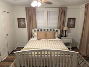 A bedroom with a white crib, a bedside table with a lamp, and a window with blinds.
