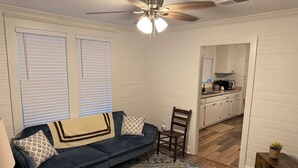 Un salon avec un canapé bleu foncé, un plaid à motifs et un tapis décoratif.