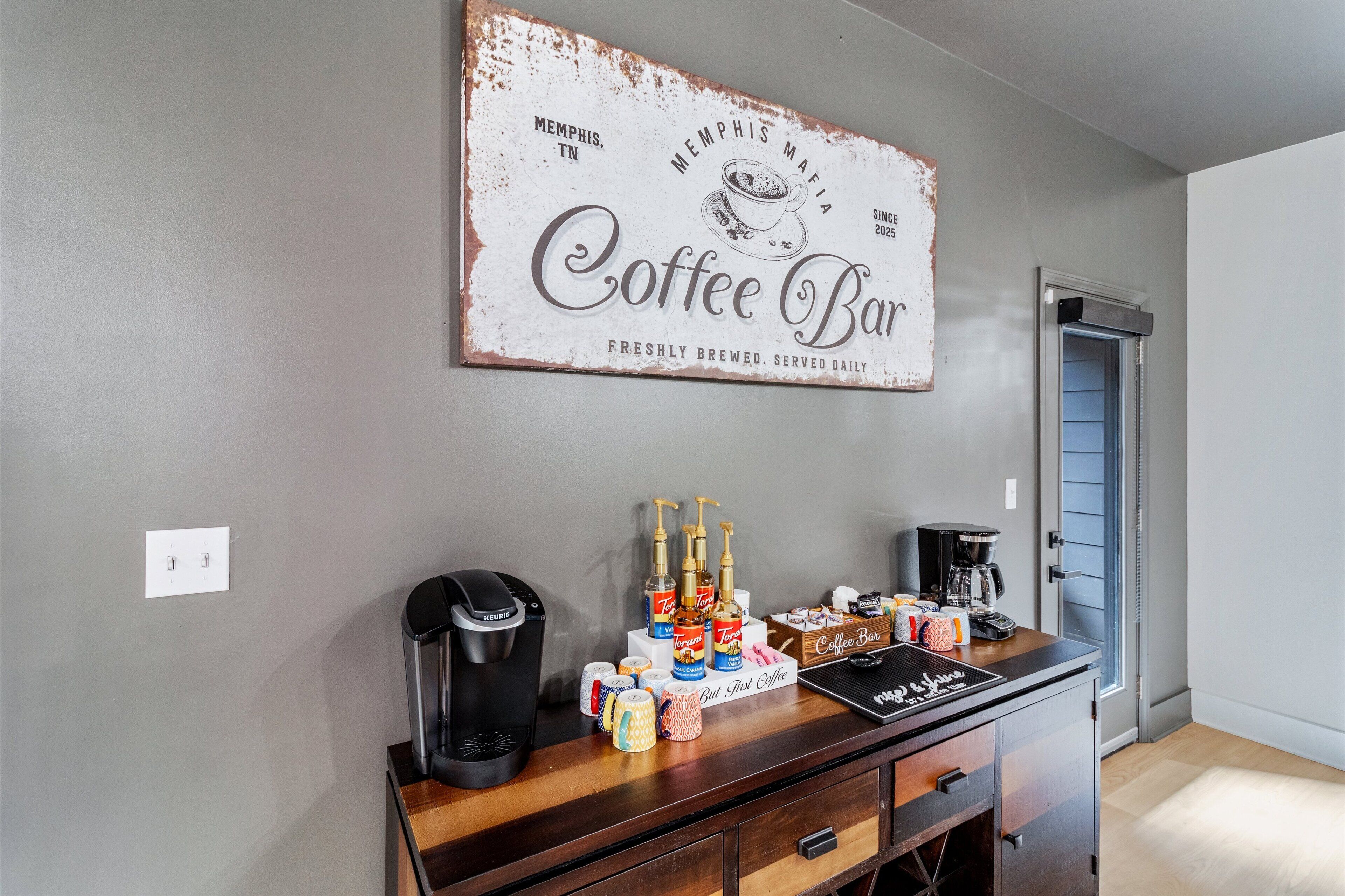 Een koffiebar met een koffiezetapparaat, espresso machine en koffiekopjes op een houten toonbank.