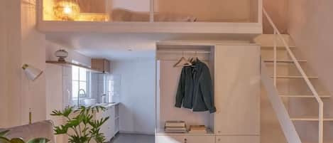 A loft-style bedroom with a bunk bed, a desk, and a hanging chair.