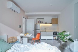 Un espacio habitable moderno y funcional, con kitchenette, comedor y cama.