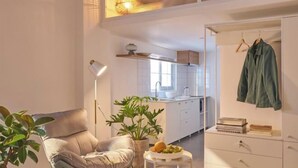 Un salon moderne avec un canapé, une petite table sur laquelle est posée une plante, et un porte-manteau suspendu.