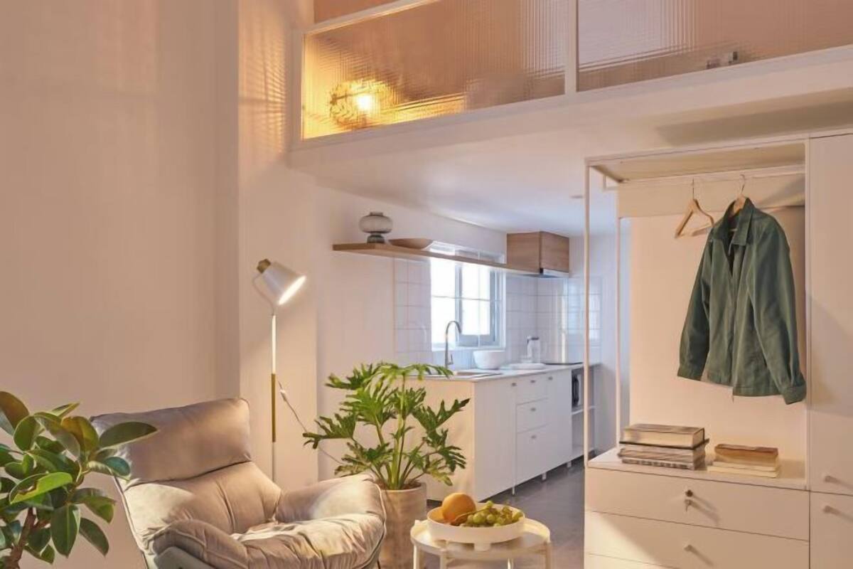 Uma sala de estar moderna com um sofá, uma mesinha com uma planta e um cabideiro suspenso.