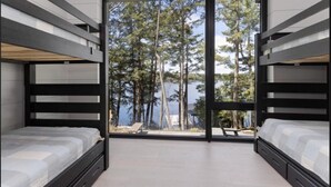 A room with bunk beds, a large sliding glass door, and a view of a lake and trees.