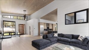 A spacious living area with a large sectional sofa, a glass coffee table, and a view of the kitchen and dining area.