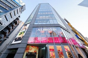 Ein modernes Gebäude mit einem markanten 'ALMOND'-Schild an der Fassade, großen Glasfenstern und einem gut sichtbaren Eingang.