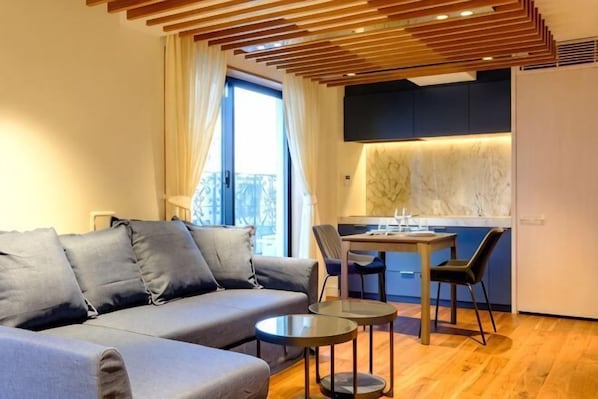 A modern living room with a sofa, a dining table, and chairs.