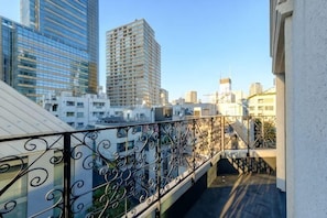 A balcony with a wrought iron railing overlooking a cityscape with modern buildings.