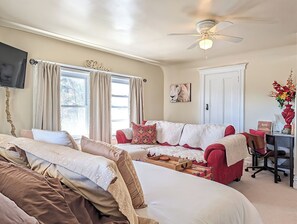 A cozy room with a bed, a sofa, a desk, and a ceiling fan.