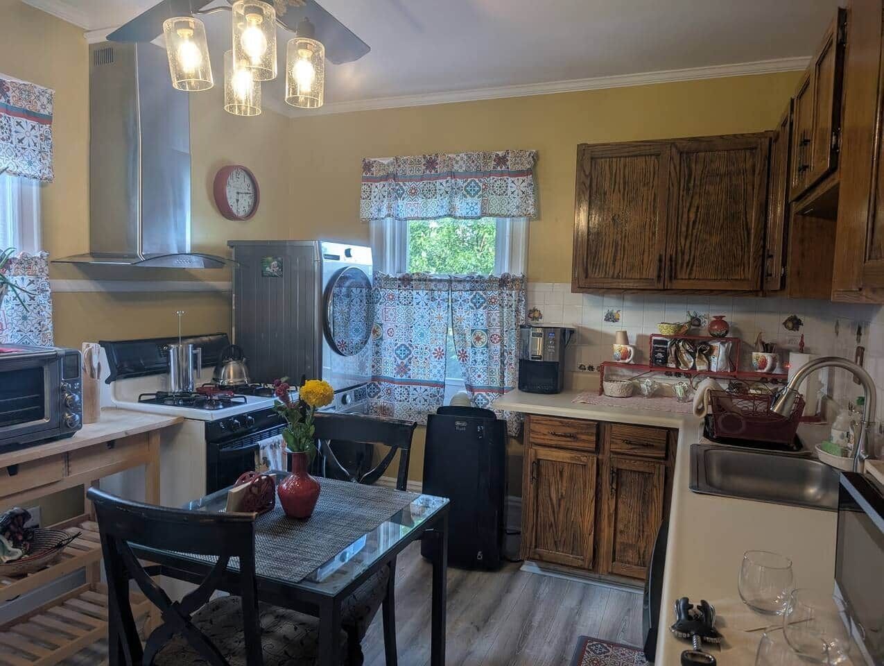 A compact kitchen with a stove, microwave, sink, and wooden cabinets.
