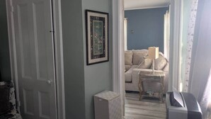 A room with a door, a framed picture, a sofa, a small table, and a lamp. - Sunny & Comfortable: Walk To Shop, Eat & NYC Train (Montclair)