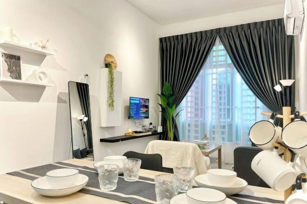 Une chambre d’hôtel moderne dotée d’un coin repas, d’une grande fenêtre avec des rideaux, d’un téléviseur fixé au mur et d’un miroir.