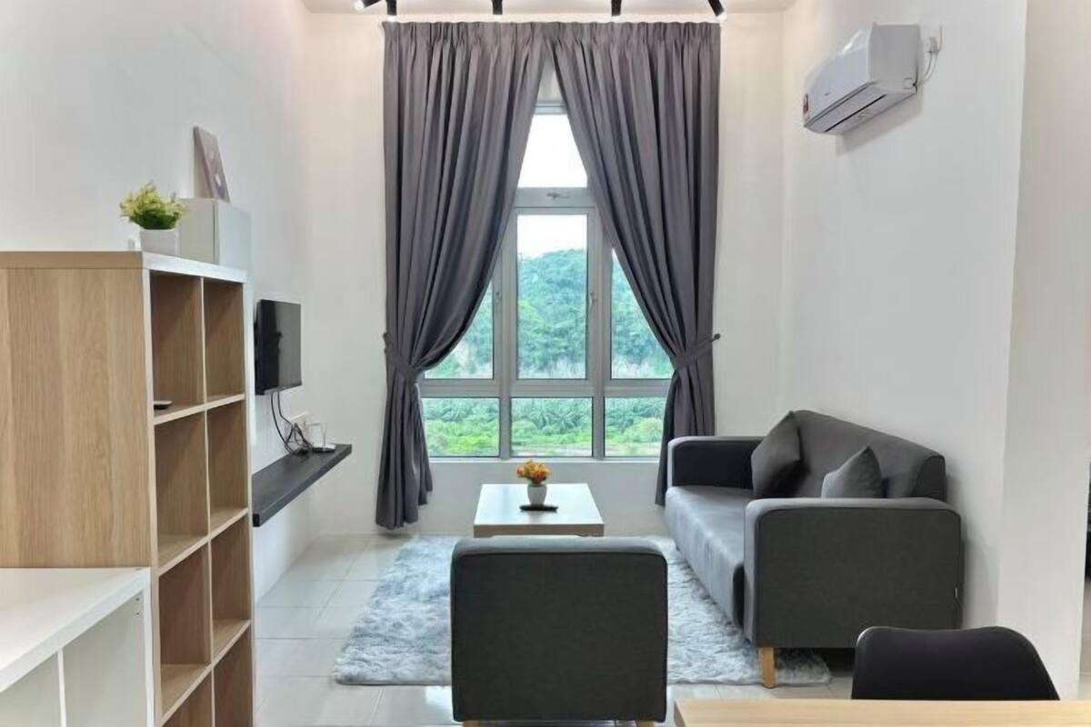 Un salon moderne avec un canapé, une table basse et un téléviseur posé sur une étagère.