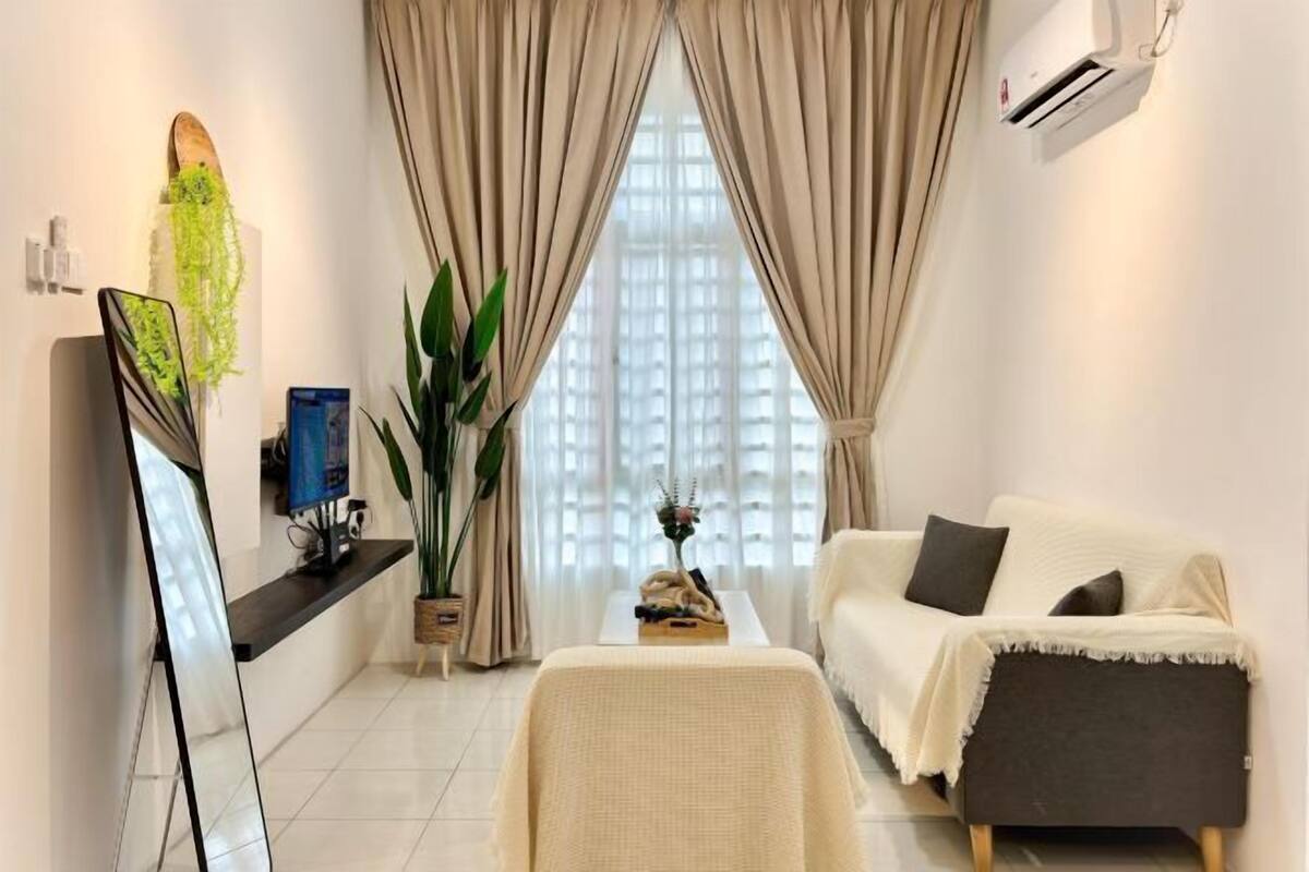 Un salon moderne avec un canapé, une table basse, un téléviseur et une grande fenêtre avec des rideaux.