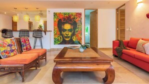 A modern living room with a wooden coffee table, a red sofa, and a colorful abstract painting on the wall. - Tropical Oasis w/ Cenote & Pool – Walk to Beach (Playa del Carmen)