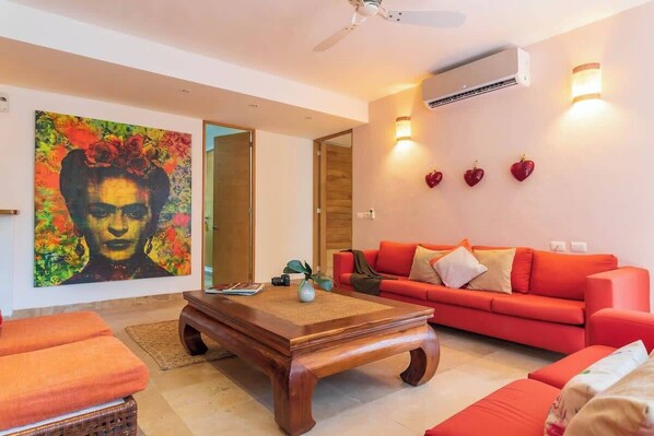 Una sala de estar moderna con un sofá rojo, una mesa de centro de madera y un cuadro abstracto y llamativo en la pared.