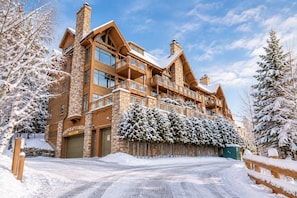 A large, multi-story lodge with a stone facade and wooden balconies, surrounded by snow-covered trees. - Tremblant Prestige - Altitude 172-11 (Mont-Tremblant)
