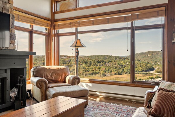 A spacious room with large windows, a fireplace, leather armchairs, and a wooden table. - Tremblant Prestige - Altitude 172-11 (Mont-Tremblant)