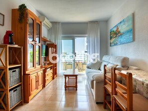 Ein Wohnzimmer mit einer Couch, Holzsäcken, einem Fernseher und einem Bild an der Wand.
