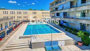 A rooftop swimming pool with a clear blue sky, surrounded by a multi-story building with balconies and air conditioning units. - Apartment in the center of Platja d'Aro with pool and A/C (Platja d'Aro)