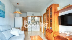 A modern living room with a sofa, wooden coffee table, and a TV. - Apartment in the center of Platja d'Aro with pool and A/C (Platja d'Aro)