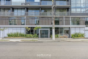 Un immeuble à plusieurs étages, doté d’une architecture moderne, avec des balcons, de grandes fenêtres et une entrée sécurisée par un portail.
