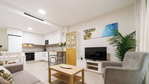 Una sala de estar moderna con un sofá, una mesa de centro, un televisor y un comedor con sillas y una mesa.