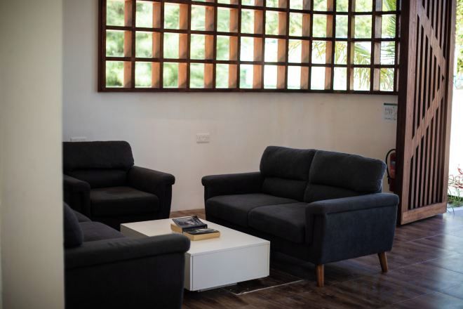 A modern living room with two dark sofas, a white coffee table, and a large window with a grid pattern.