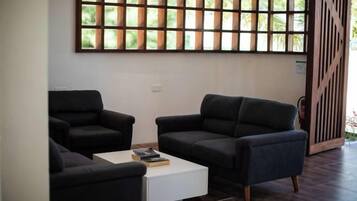 A modern living room with two dark sofas, a white coffee table, and a large window with a grid pattern.