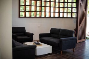 A modern living room with two dark sofas, a white coffee table, and a large window with a grid pattern. - Heron Beach Hotel Dhiffushi (Dhiffushi)