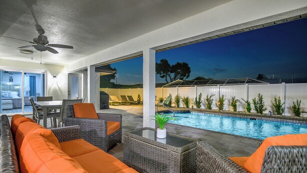 Zona de piscina exterior con mobiliario de mimbre y vista a la piscina.