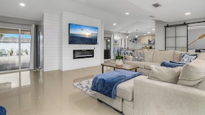 Una sala de estar moderna con un televisor de pantalla plana grande, un sofá color beige y una mesa de centro.