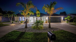 Una casa residencial con entrada de vehículos, palmeras y un buzón.