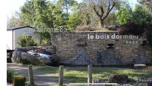 A stone wall with a sign that reads "le bois dormant" and a small pond.