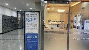 A reception area with a sign explaining check-in procedures, a glass door with the SKY TOP HOTEL logo, and a wall with check-in boxes. - Skytop INN-TheCity unseo (Incheon)