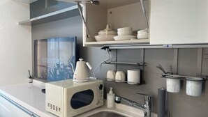 A modern kitchen with a microwave, sink, and shelves with dishes and utensils. - Skytop INN-TheCity unseo (Incheon)