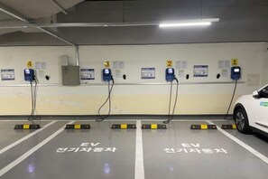 An EV charging station area with four charging points, marked parking spaces, and informational signs. - Skytop INN-TheCity unseo (Incheon)