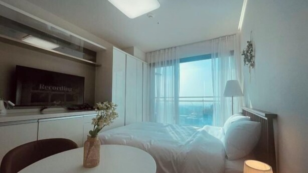 A hotel room with a bed, a desk with a computer, a round table with a vase, and a window with curtains. - Skytop INN-TheCity unseo (Incheon)