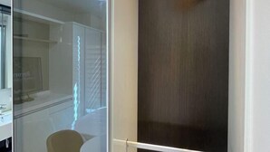A bathroom with a glass partition, a white sink, and a wooden towel rack. - Skytop INN-TheCity unseo (Incheon)