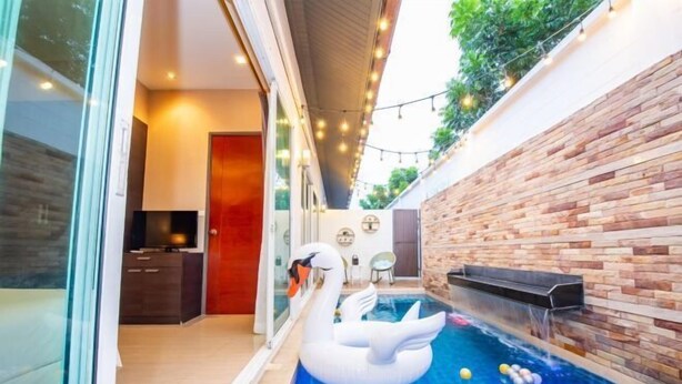 A modern indoor pool with a swan float, a brick wall, and string lights. - Aurora Life Pool Villa Pattaya (Pattaya)