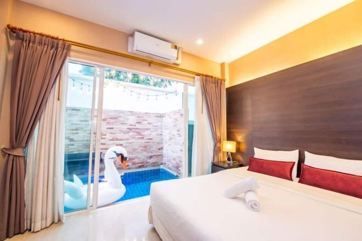 Une chambre d’hôtel avec un lit, une table de chevet, une lampe, une fenêtre avec des rideaux et une vue sur une piscine où nage un cygne.