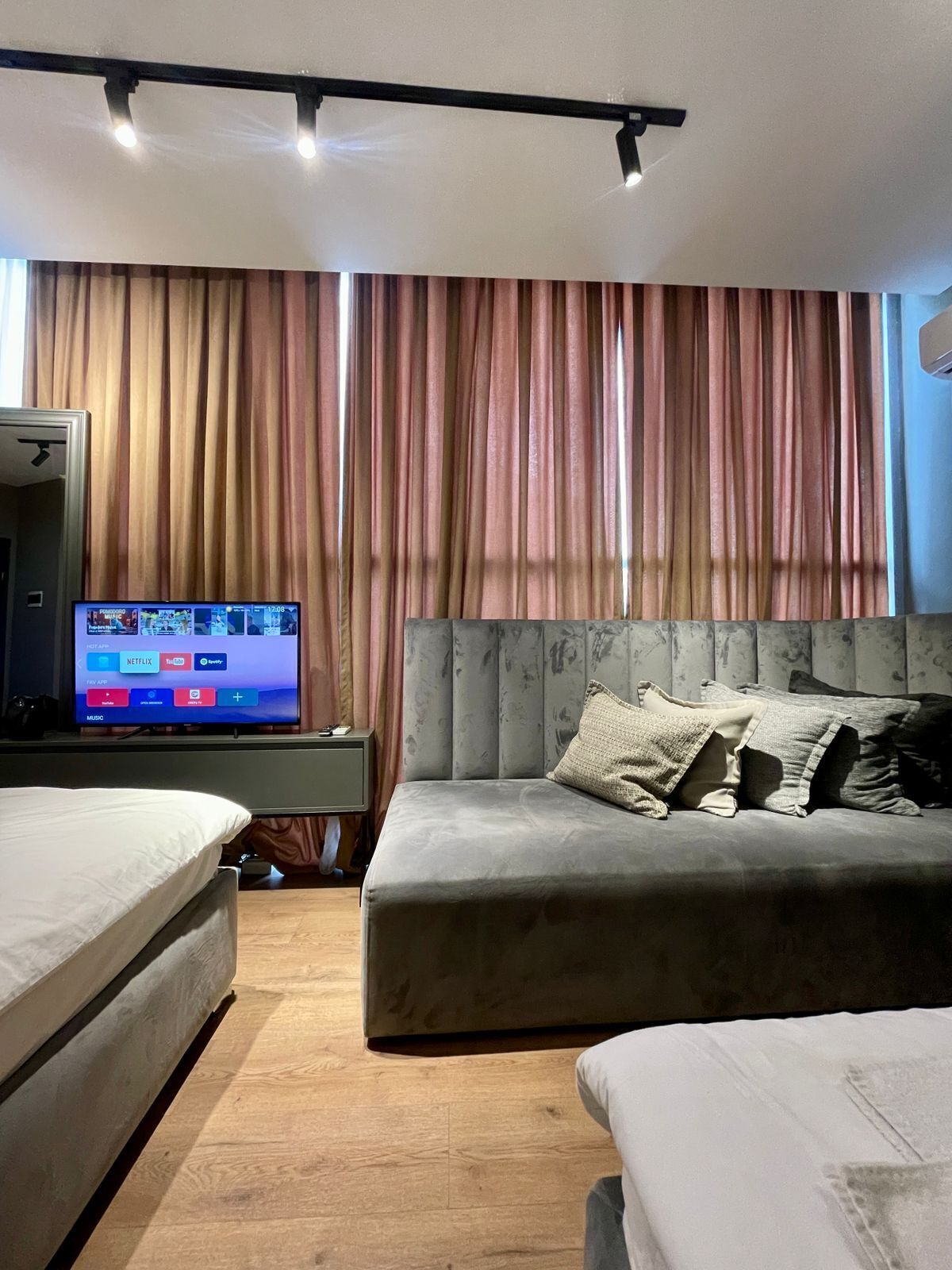 Een hotelkamer met een bed, een bank, een televisietoestel waarop streamingdiensten worden afgespeeld en een gordijn.
