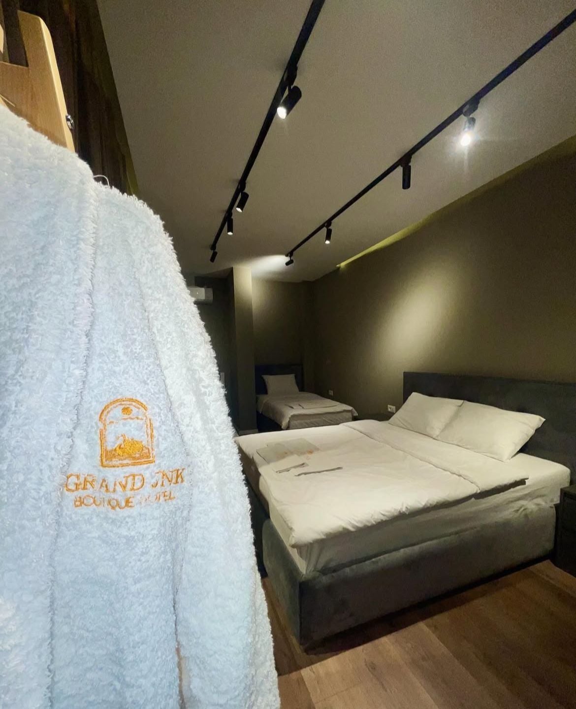 Una habitación de hotel con una cama, una mesita de noche y una bata colgada en un perchero.