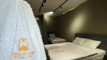 Una habitación de hotel con una cama, una mesita de noche y una bata colgada en un perchero.