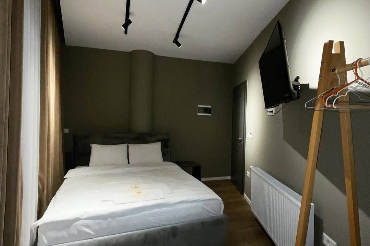 Ein modernes Schlafzimmer mit einem Bett, einer Holzkommode, einem an der Wand befestigten Fernseher und einer Heizung.
