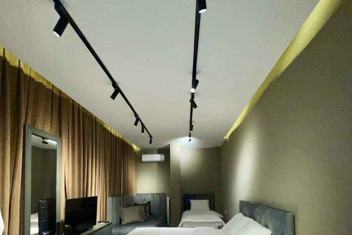 Ein modernes Hotelzimmer mit einem großen Bett, einem Fernseher auf einem Schrank und einem Schreibtisch mit Stuhl.